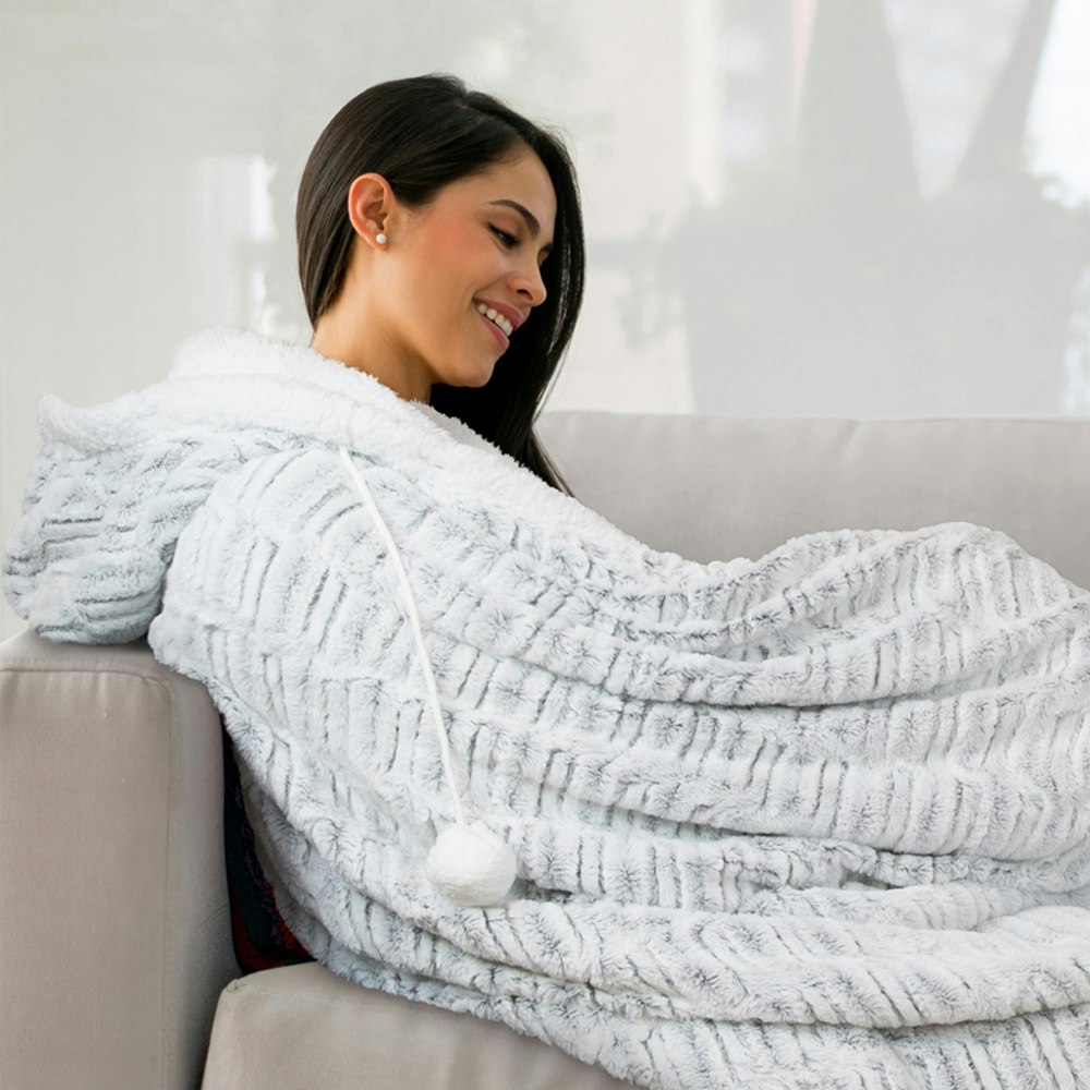 Girl sitting on a couch with the ardor hooded faux fur blanket