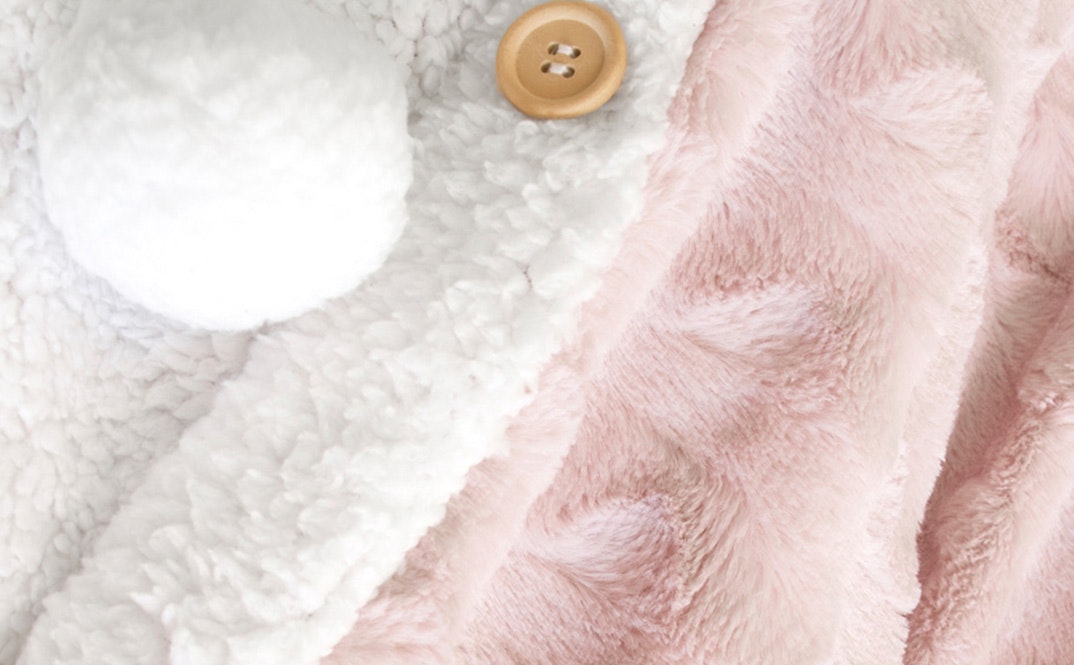Girl sitting on a couch with the ardor hooded faux fur blanket